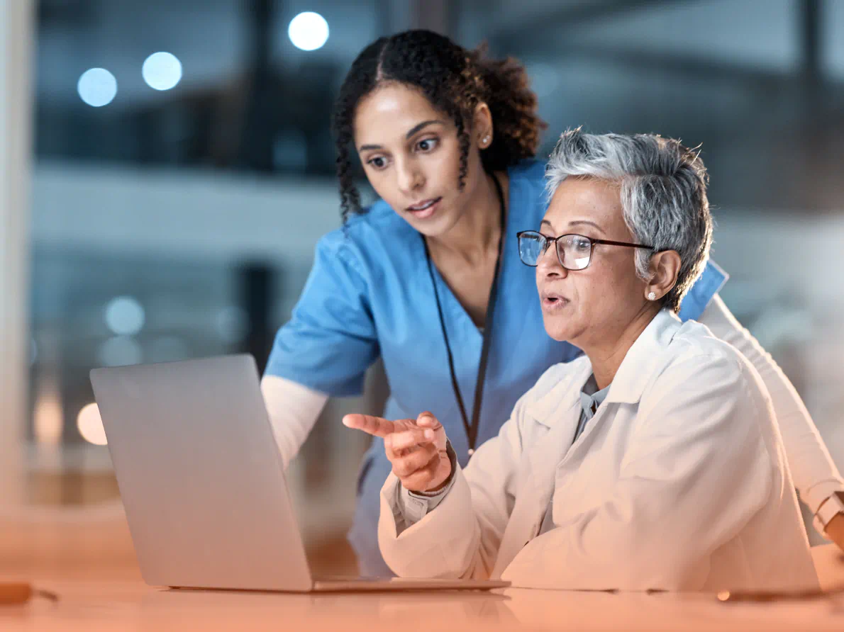 Coworkers in medical environment looking at laptop together