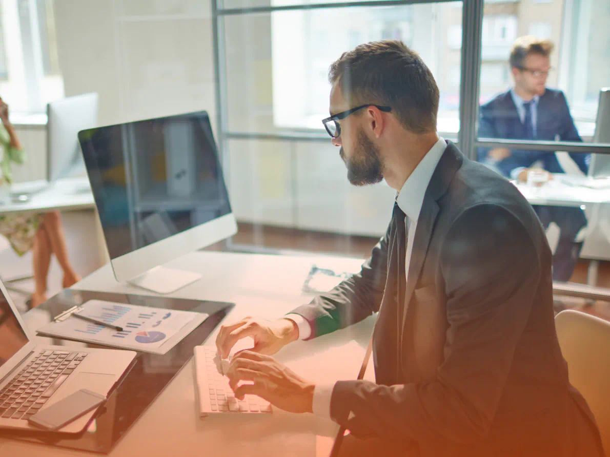 Business man in suit sitting at a desk while using a computer