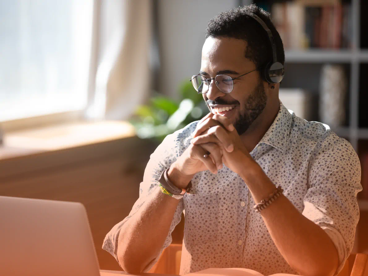 Man smiling wearing headset and looking at laptop computer