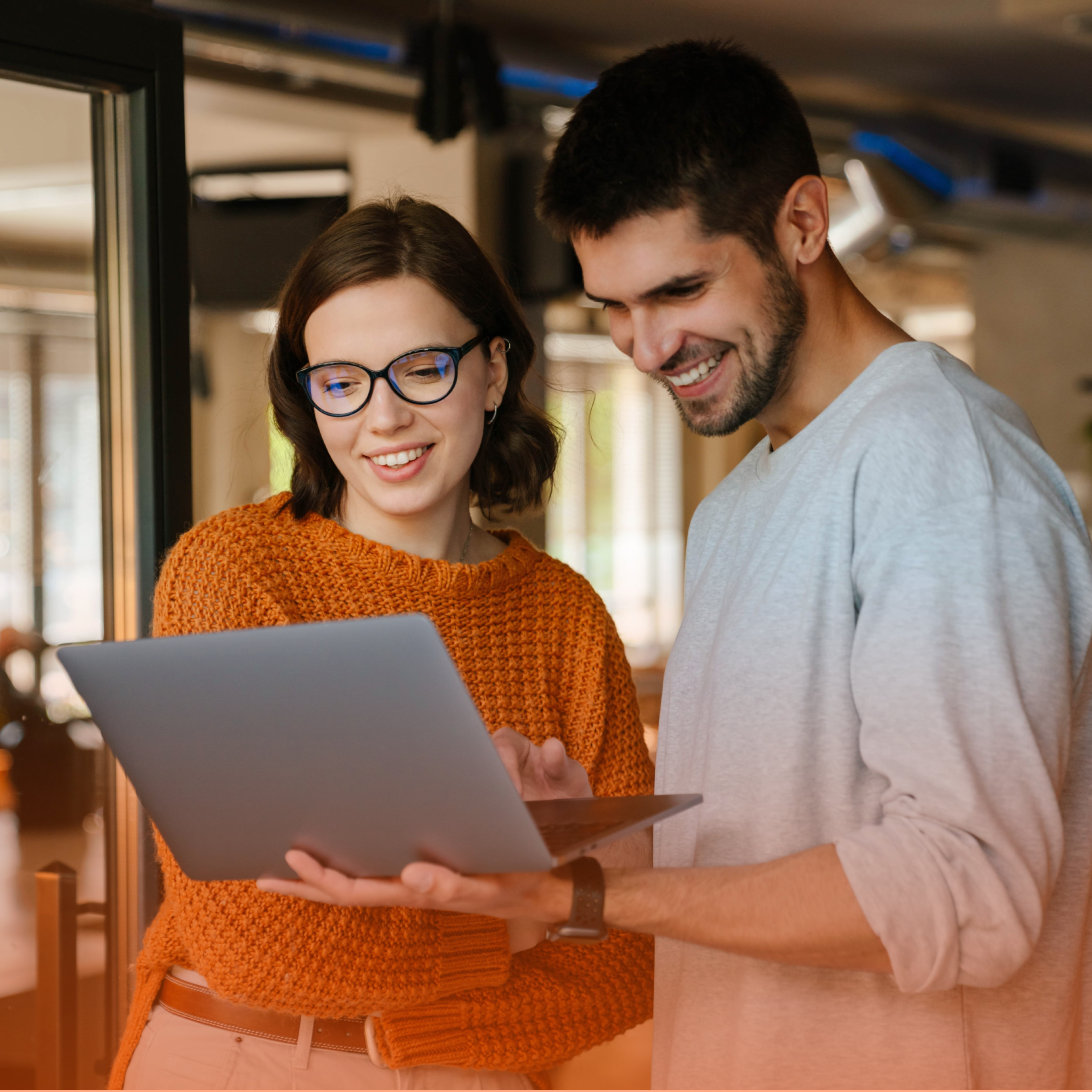 Man and woman smiling and looking at laptop computer