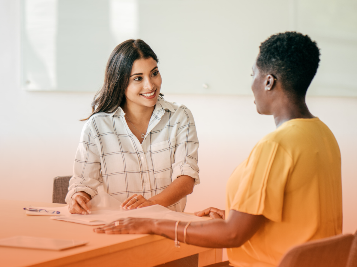 Two females having a discussion while sitting at table