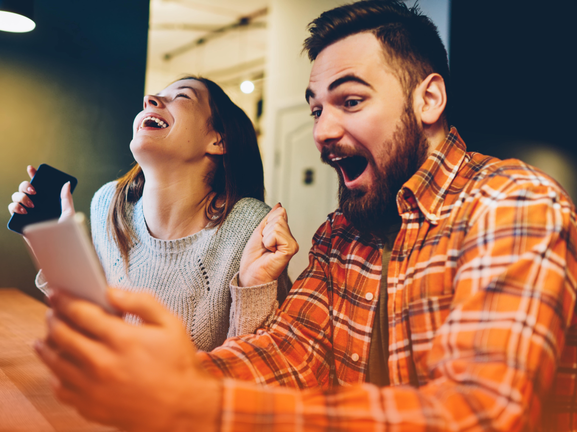 Two people excitedly celebrating with mobile devices