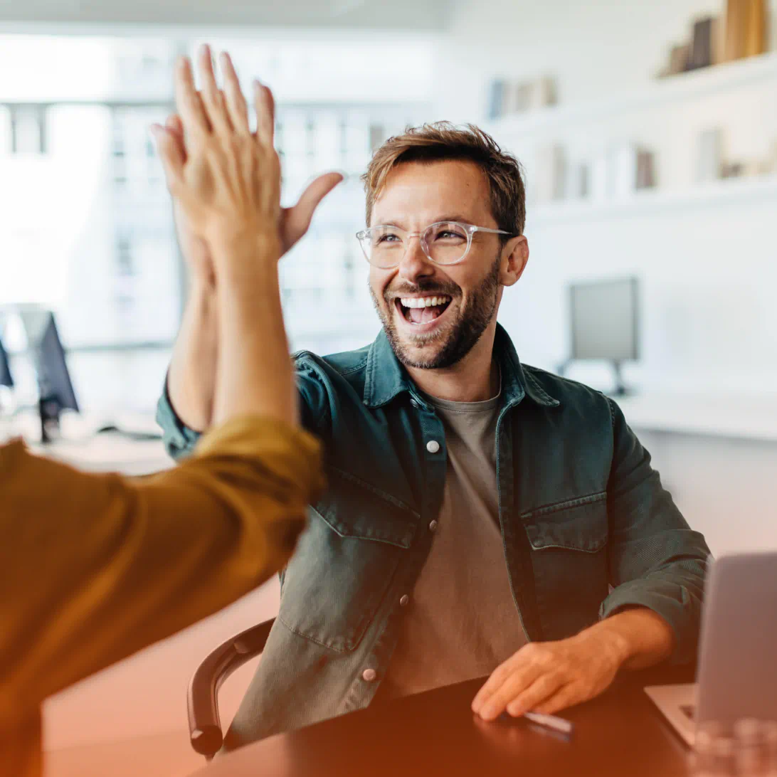 Man smiling and high fiving a coworker