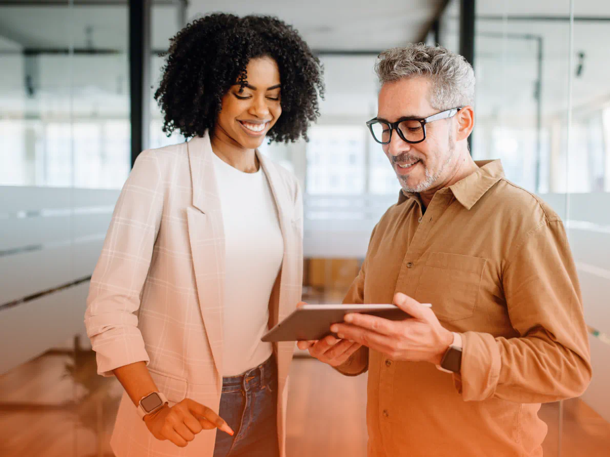 Coworkers smiling and sharing a tablet device