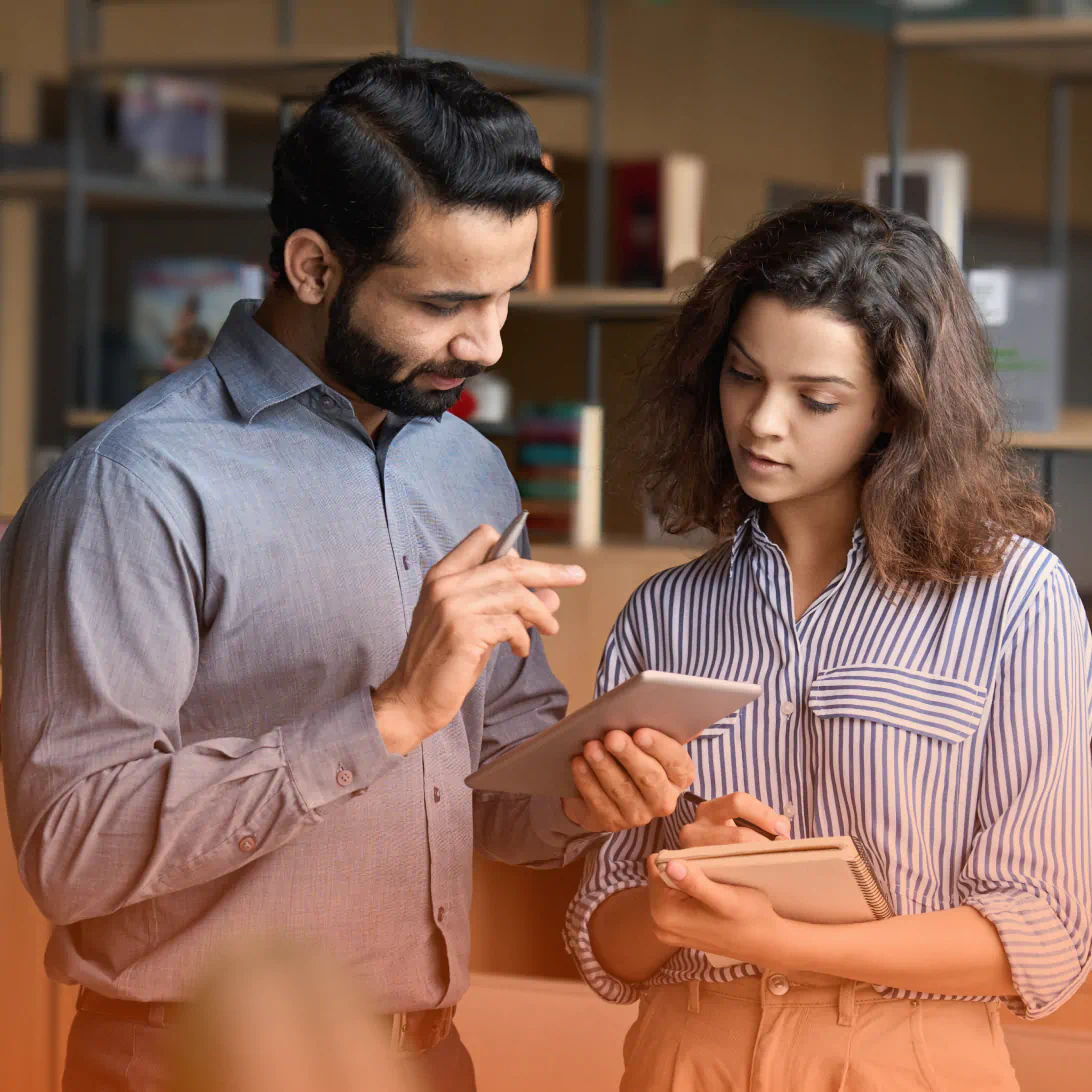 Two coworkers looking at tablet device together