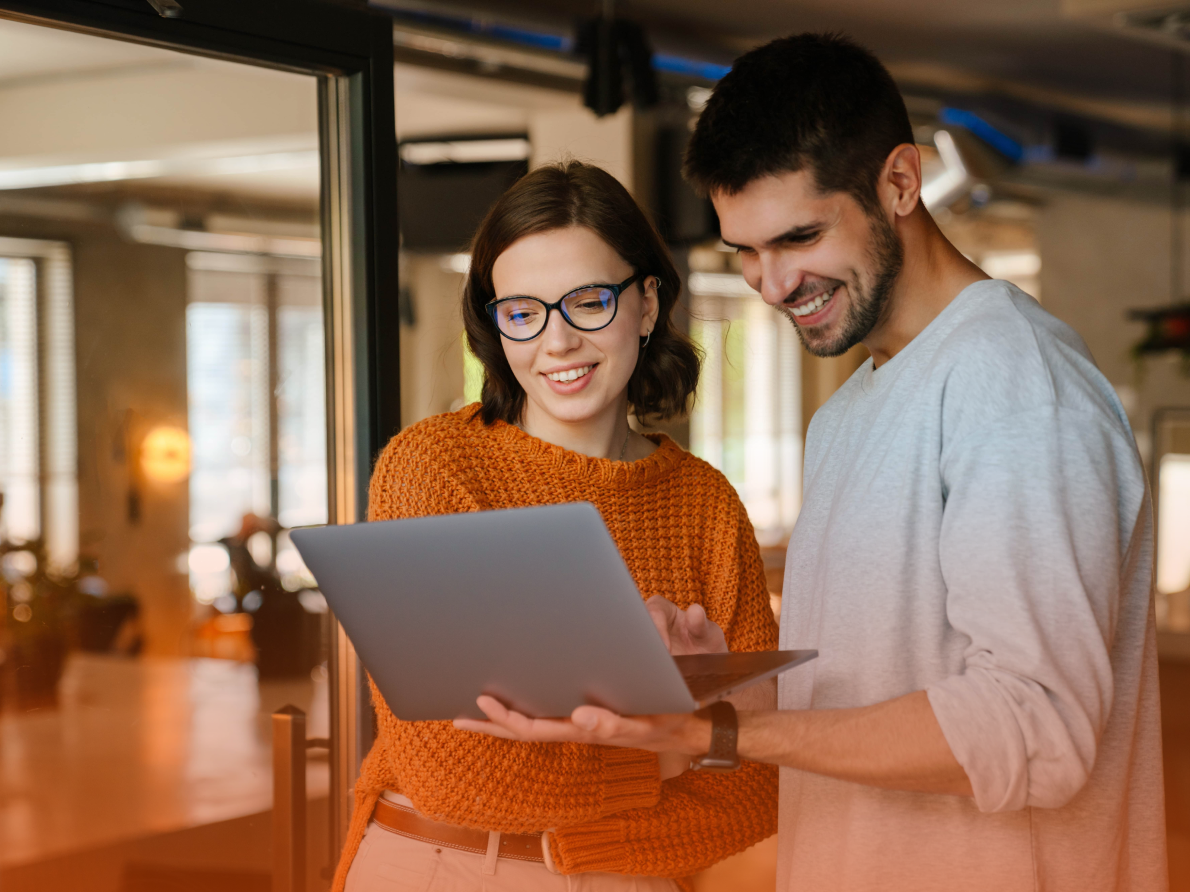 Man and woman smiling and looking at laptop computer
