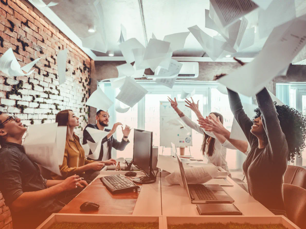 Professional team in conference room throwing papers in the air