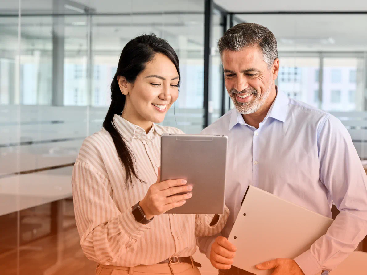 Woman and man smiling and looking at tablet device