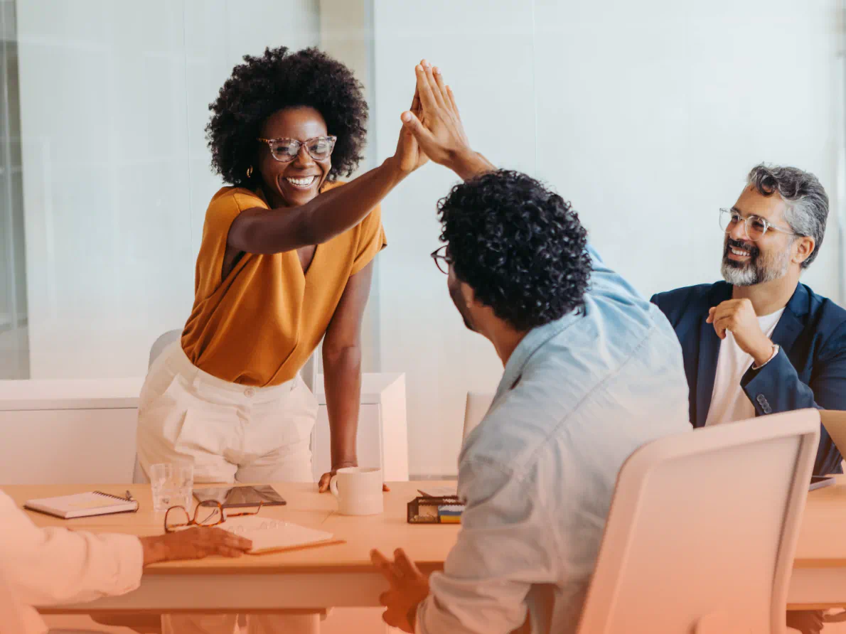 Two professionals high fiving in conference room